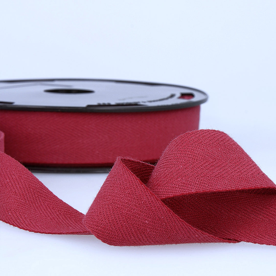 Red twill herringbone tape on a spool on a white background